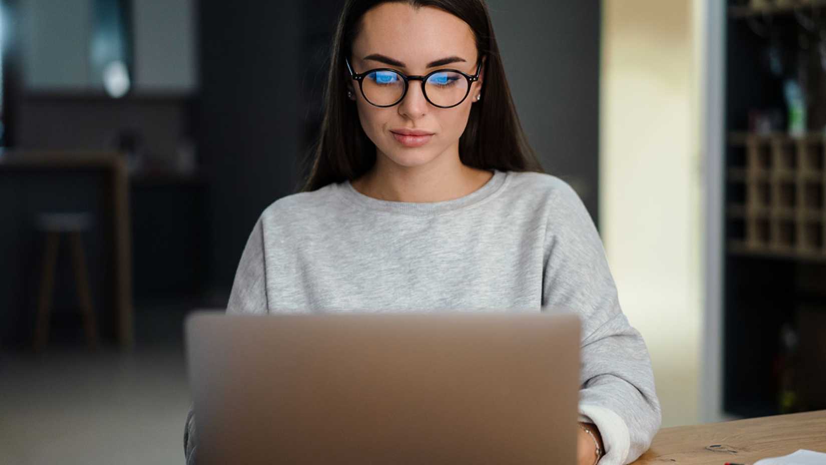A woman looks down at her laptop.