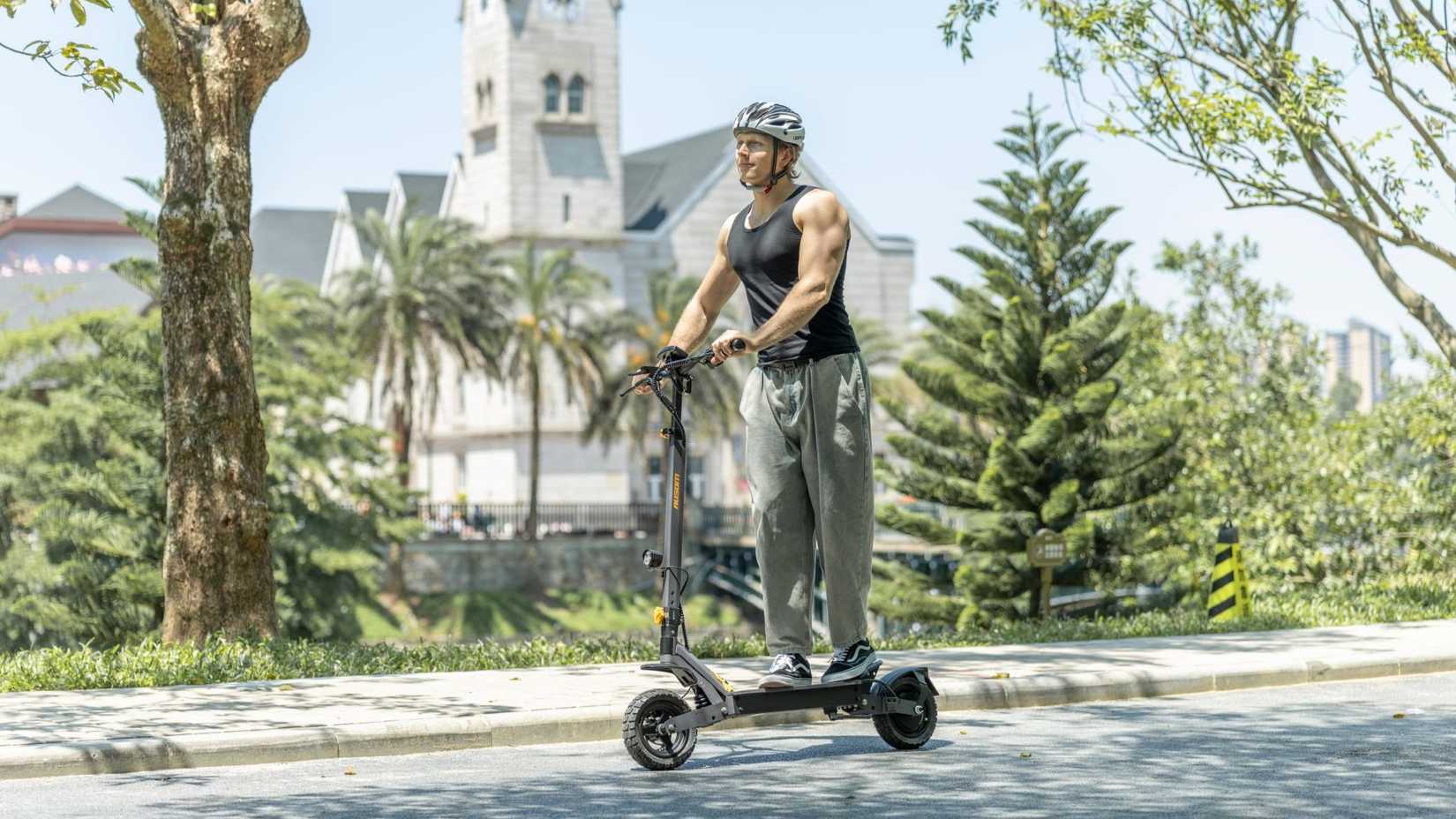 man riding an Ausom L1 scooter on a road
