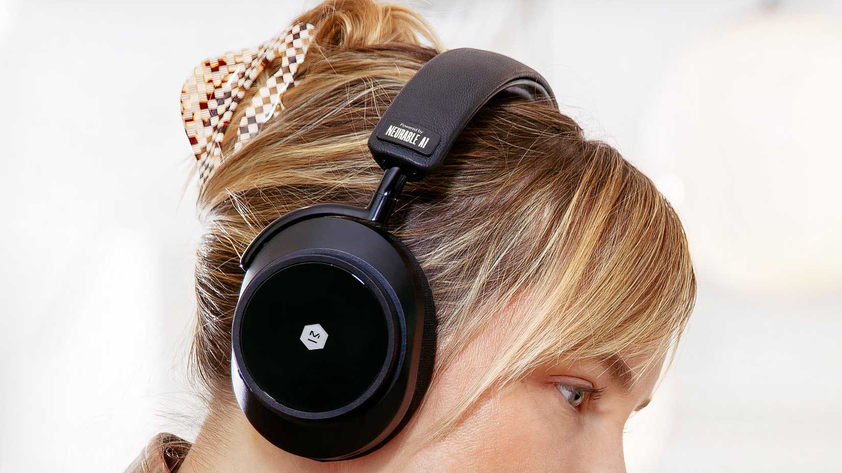 A blonde woman wears the Neurable MW75 Neuro LT headphones