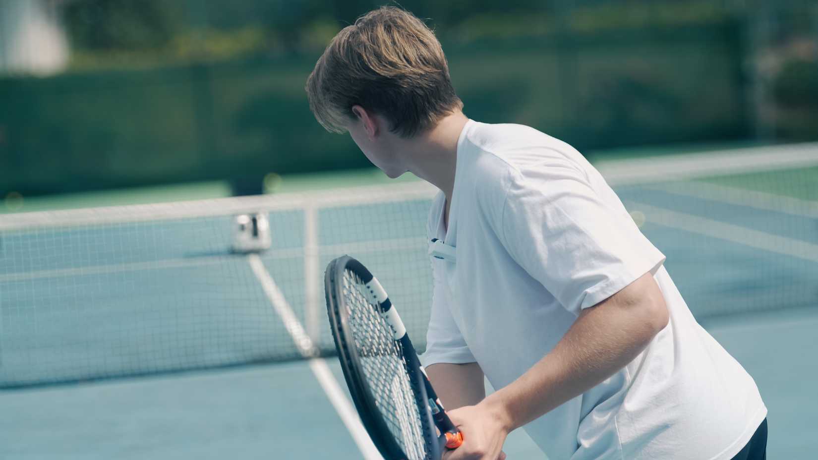 pongbot pace s pro in the distance with a tennis player ready to swing