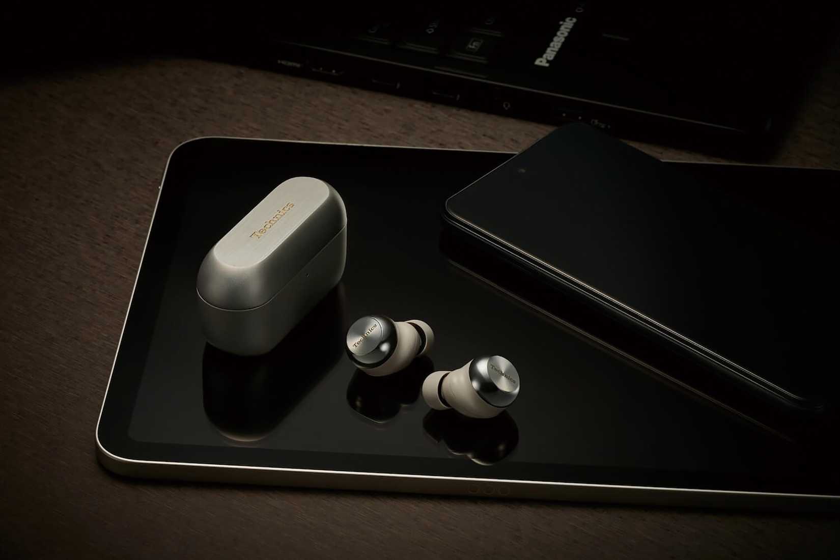 The Panasonic Technics EAH-AZ100 earbuds atop a phone and tablet.