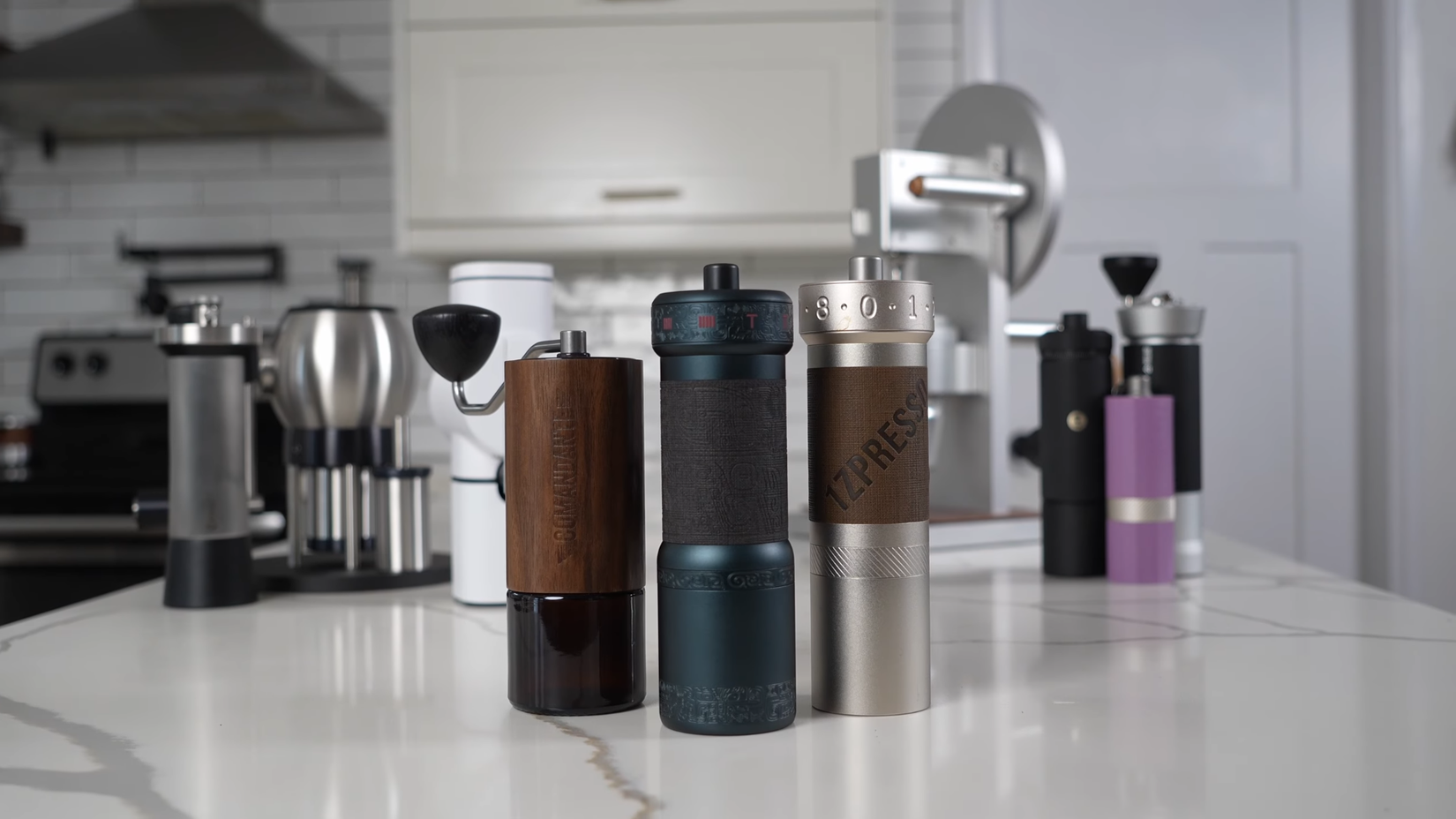 Unos cuantos molinillos de café de manivela colocados sobre una encimera de mármol.