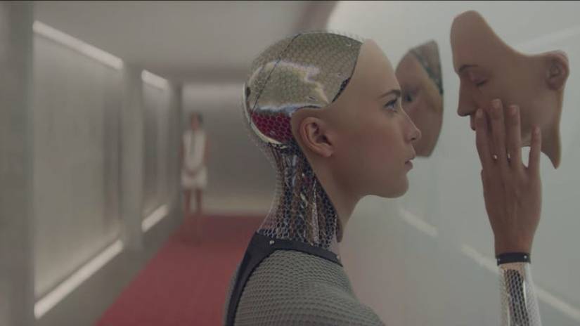 Ava examines a face in Ex Machina, with Kyoko in the background