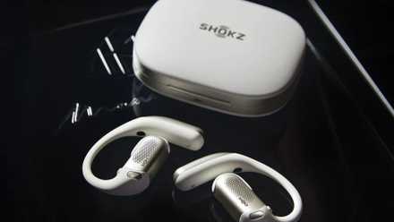 The Shokz OpenFit Pro and case, in white, sitting on a flat surface