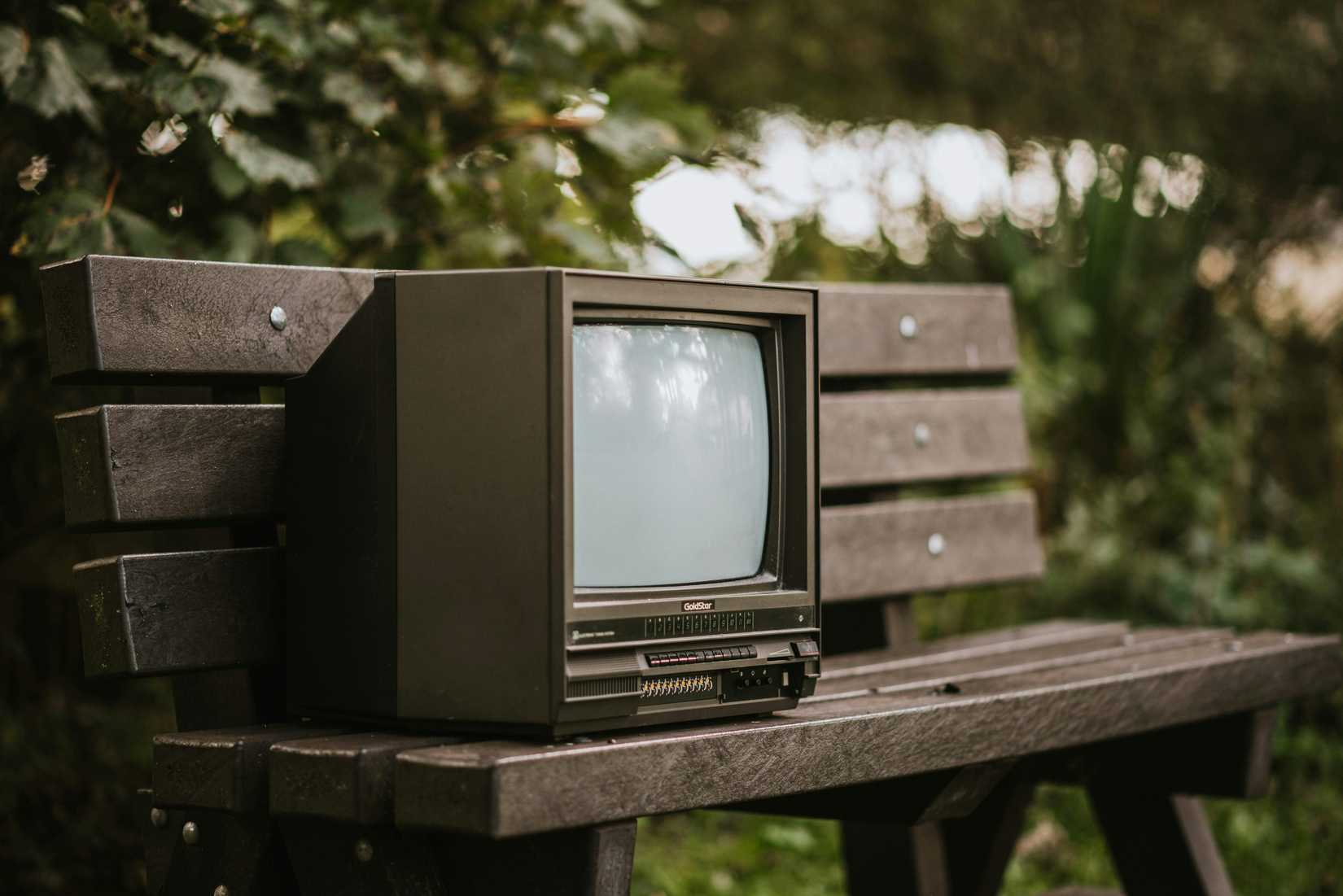 An old TV on a park bench