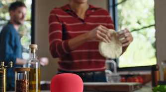 A Google Home Speaker in Berry, sitting on a kitchen counter.