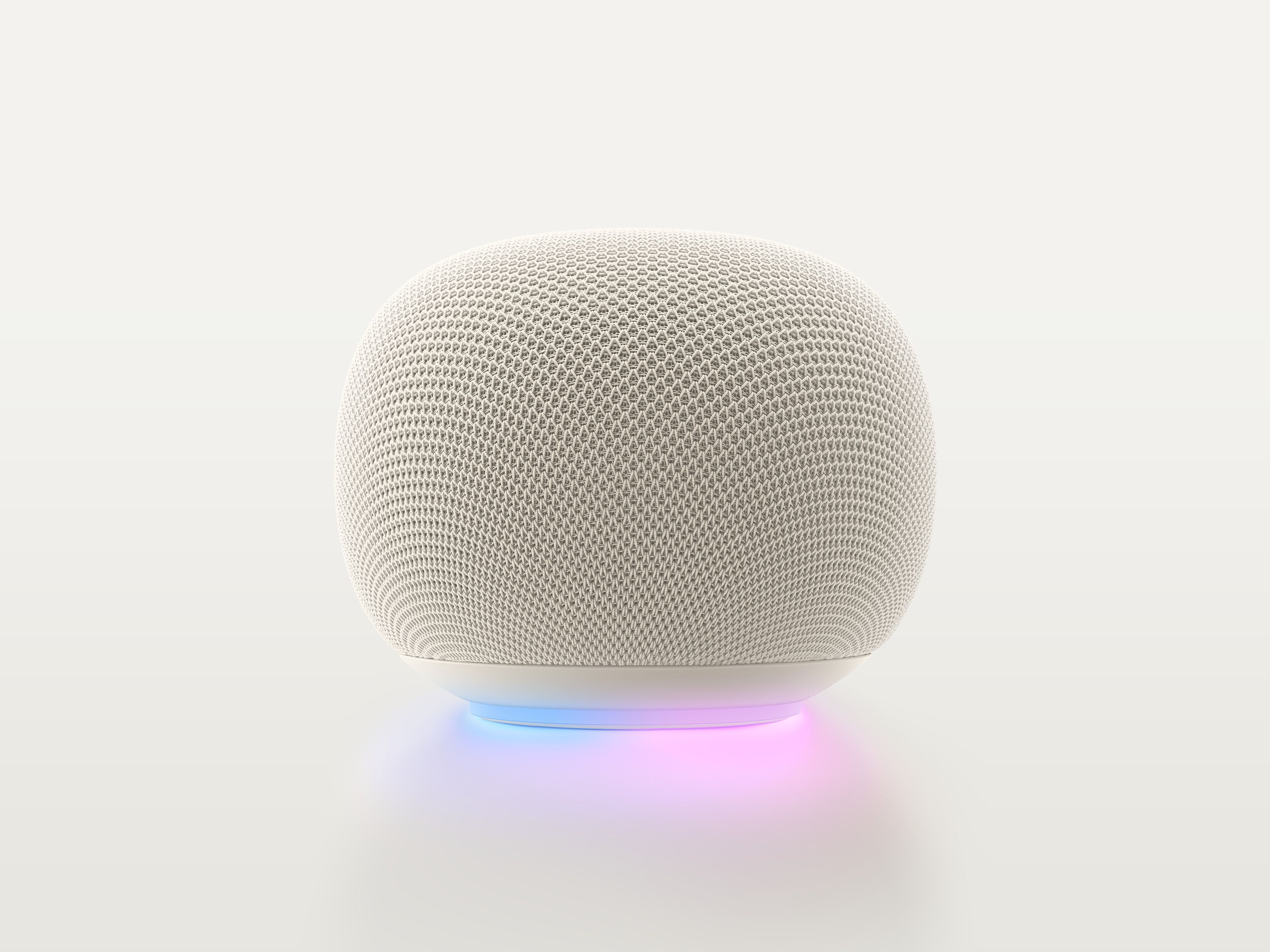 A Google Home Speaker in Porcelain, with the light ring glowing blue and purple.