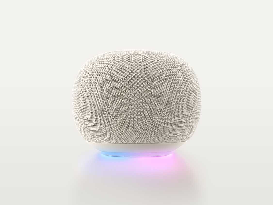 A Google Home Speaker in Porcelain, with the light ring glowing blue and purple.