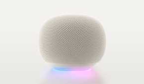 A Google Home Speaker in Porcelain, with the light ring glowing blue and purple.