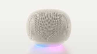 A Google Home Speaker in Porcelain, with the light ring glowing blue and purple.