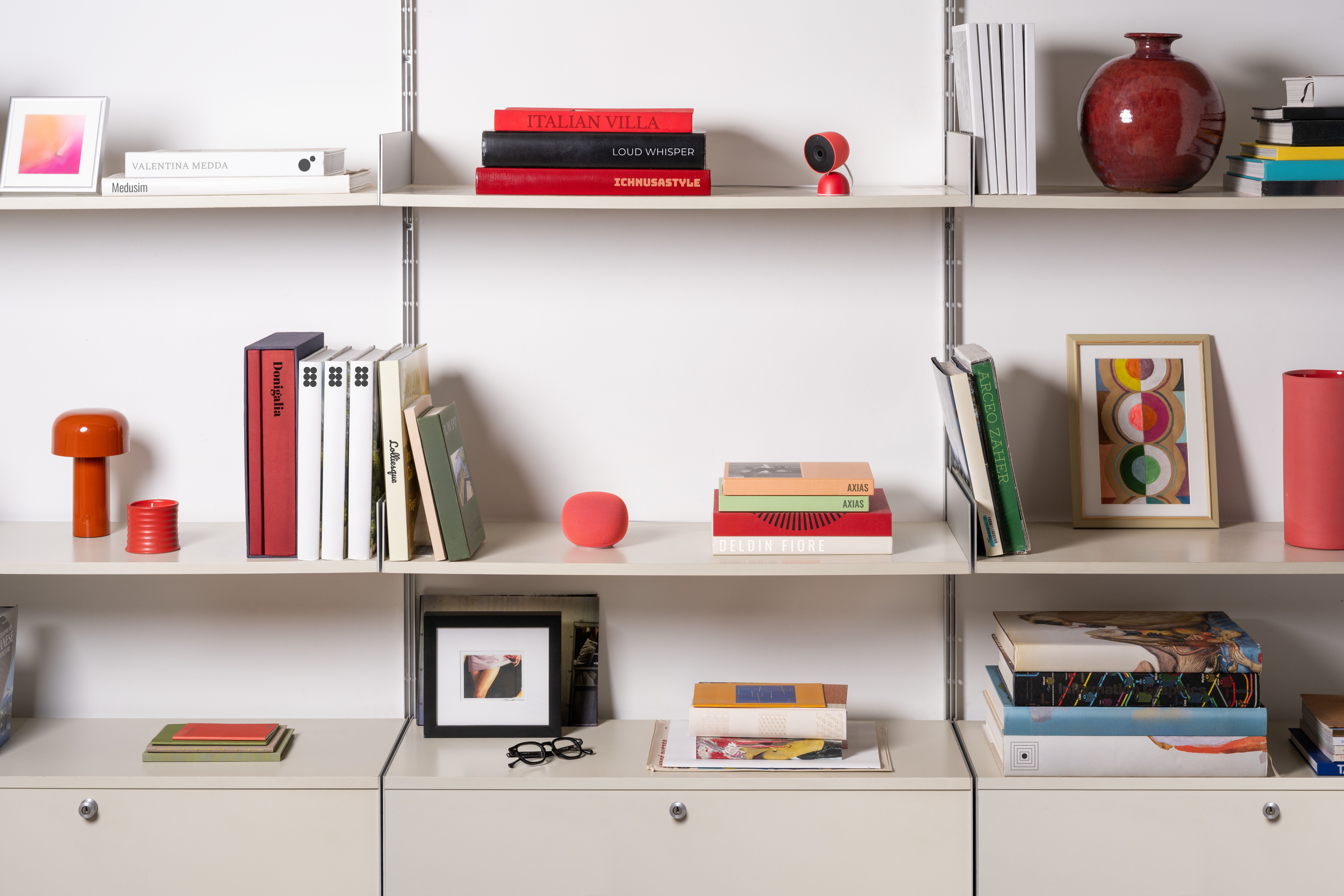 The Google Home Speaker in Berry sitting on a shelf.