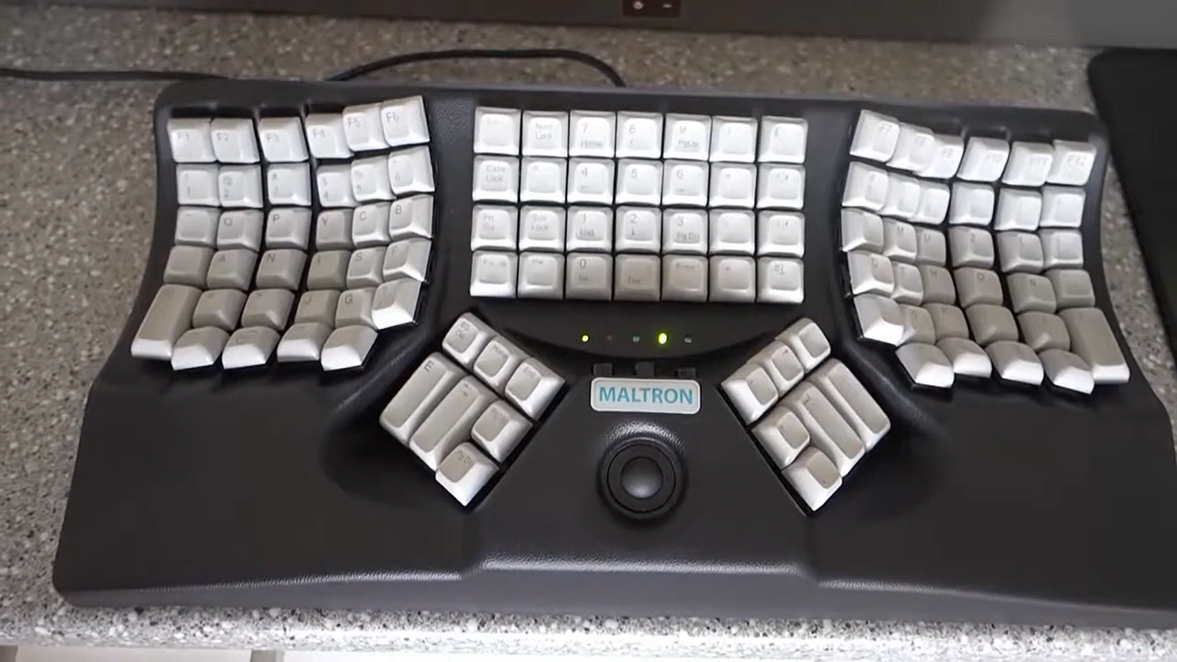 Maltron ergonomic keyboard on a speckled surface.