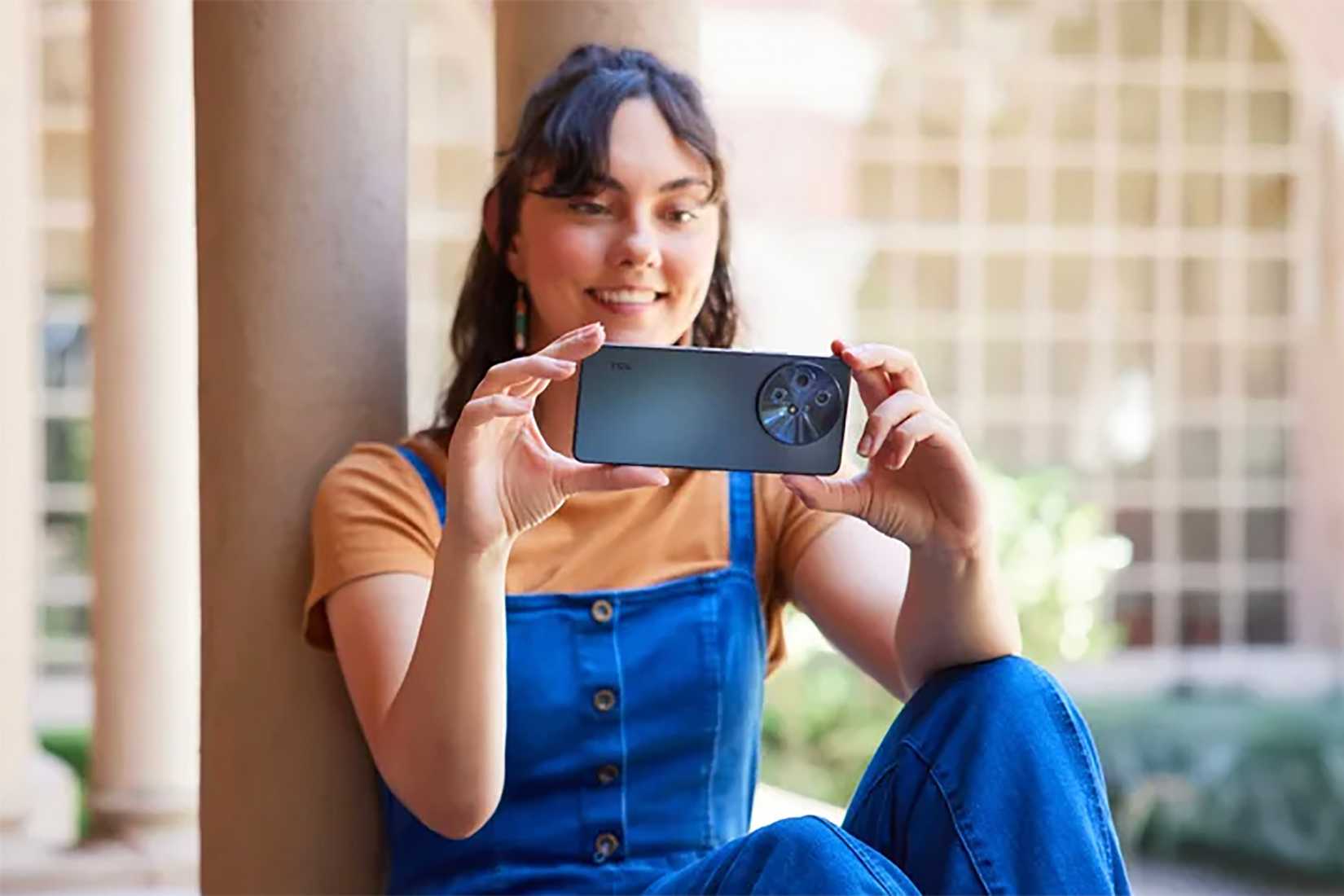 Une femme tenant un téléphone TCL 60 XE NxtPaper à la verticale. 