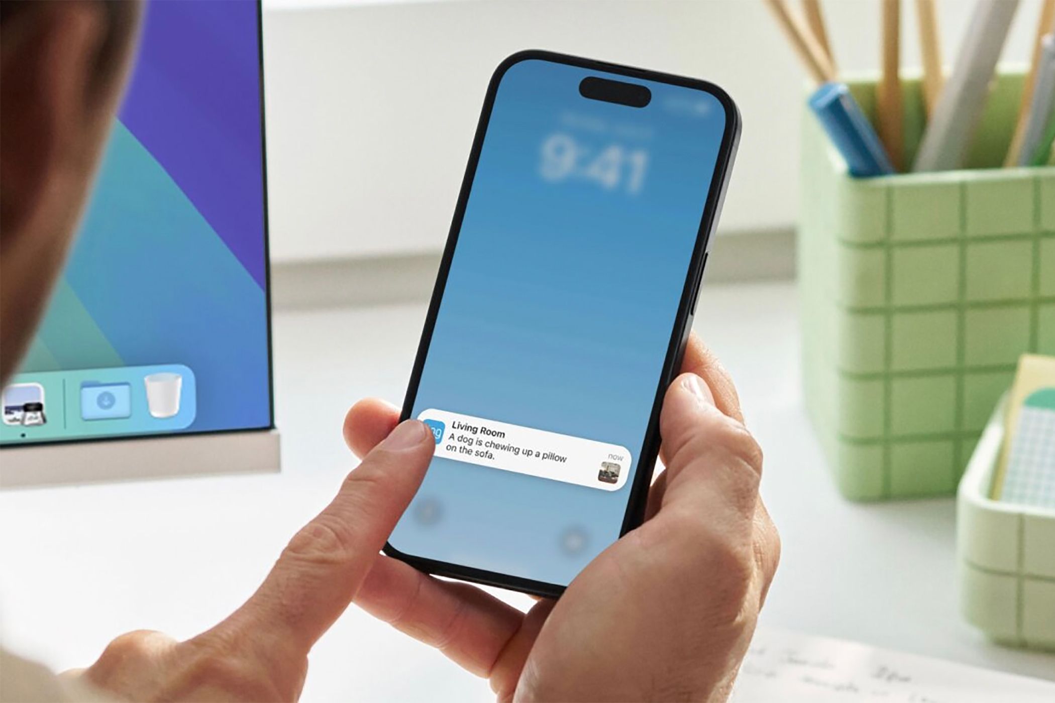 A finger touching a phone showing a Ring notification about a dog chewing furniture.