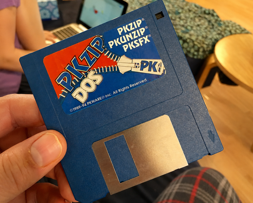 Hand holding a blue PKZIP floppy disk