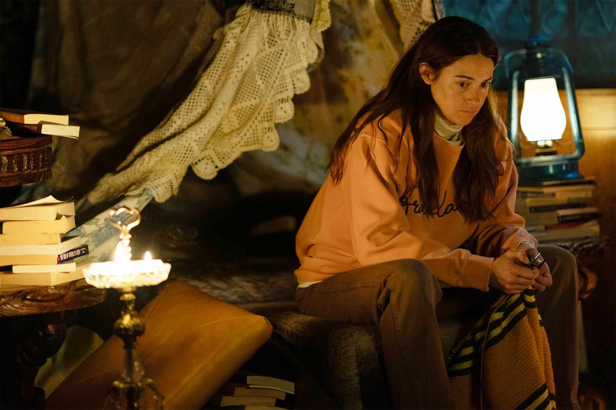 Annie in a sweater sitting on a bed thinking in Paradise.