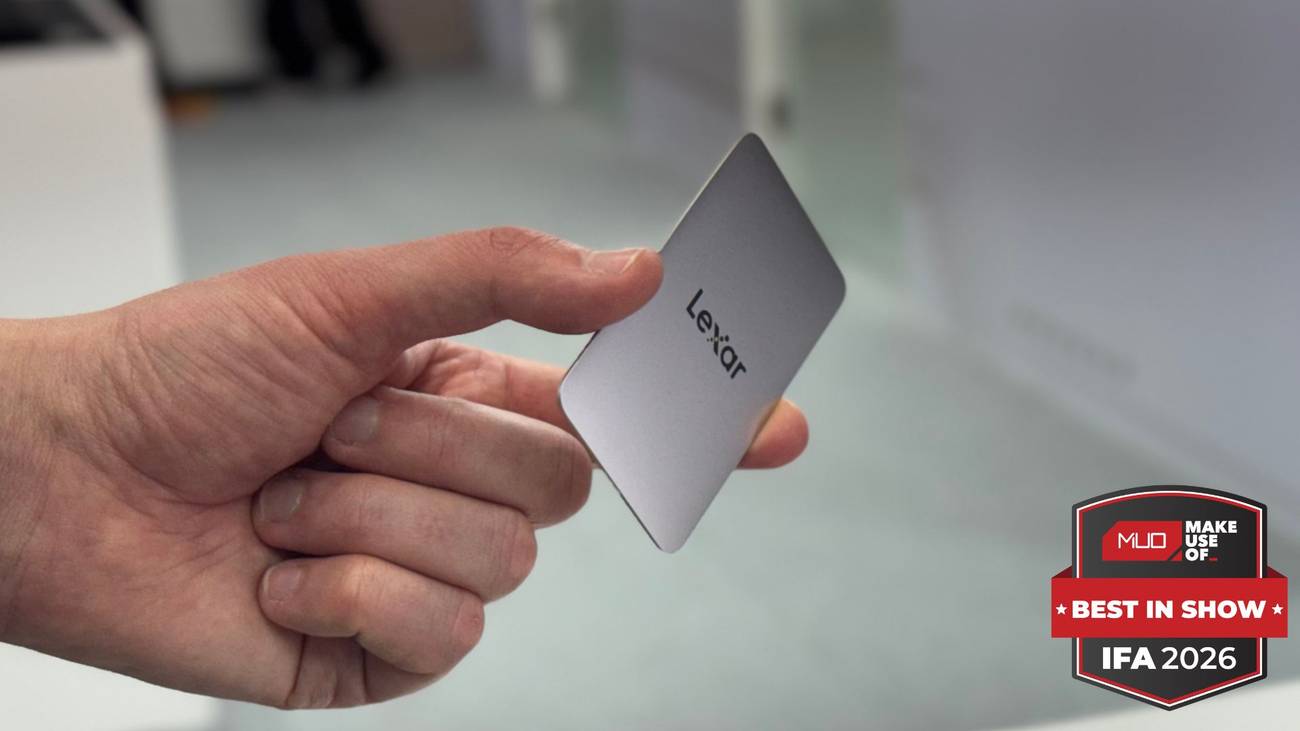 Hand holding a small silver Lexar portable SSD, roughly credit-card sized