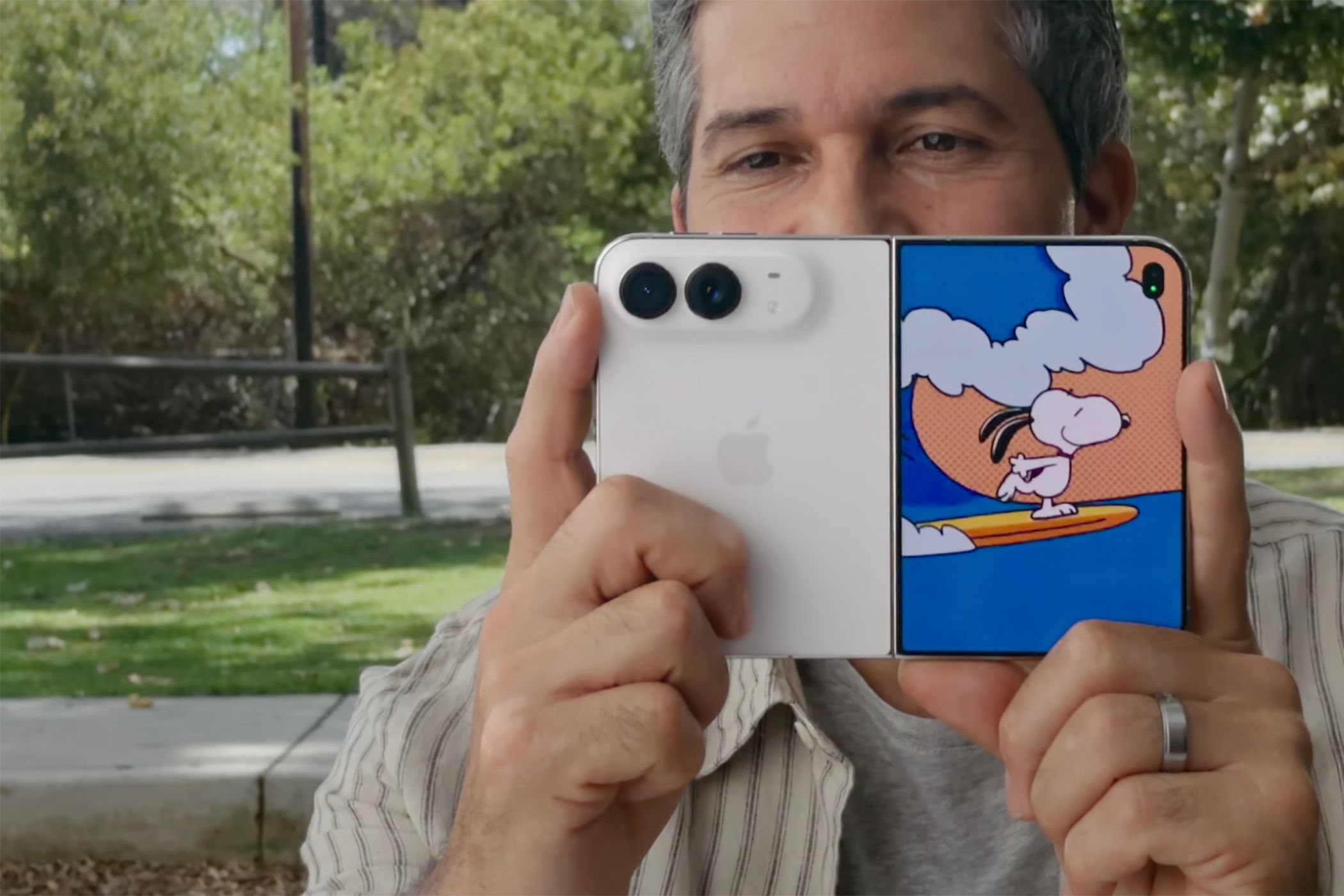 A man holding the iPhone Duo up with a Kid Cue Peanuts animation on the front screen.