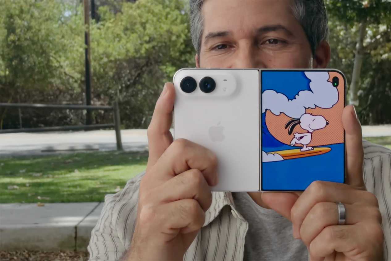A man holding the iPhone Duo up with a Kid Cue Peanuts animation on the front screen.