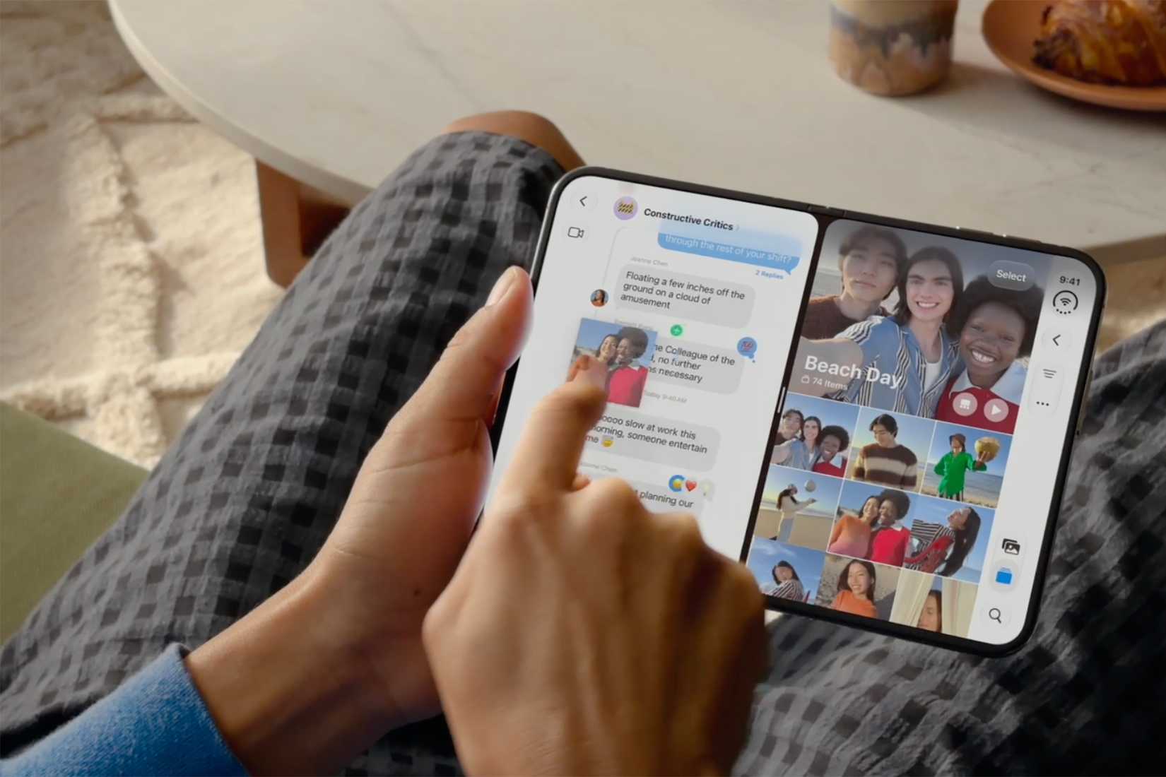 A hand holding an iPhone Duo on their lap looking at two screens at once on the inner screen.