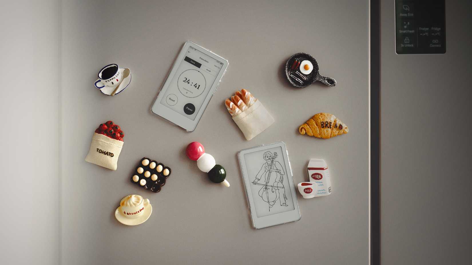 A refrigerator door decorated with magnetic miniature e-reader devices and various food-themed magnets like coffee and pastries.