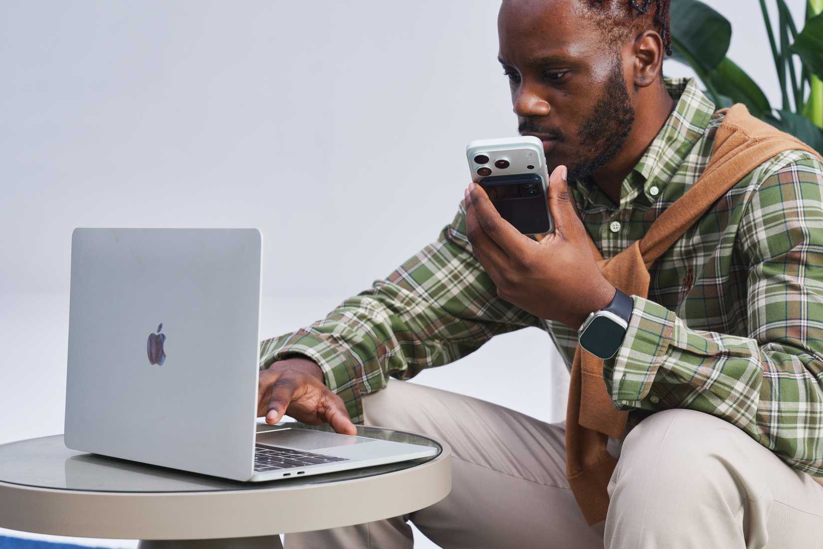 Man working on his computer with his phone in hand that has the Comu Action Pro attached.