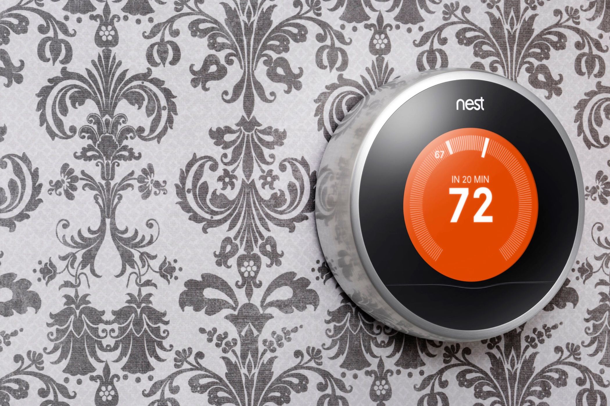 A first-generation Nest learning thermostat in a press image.
