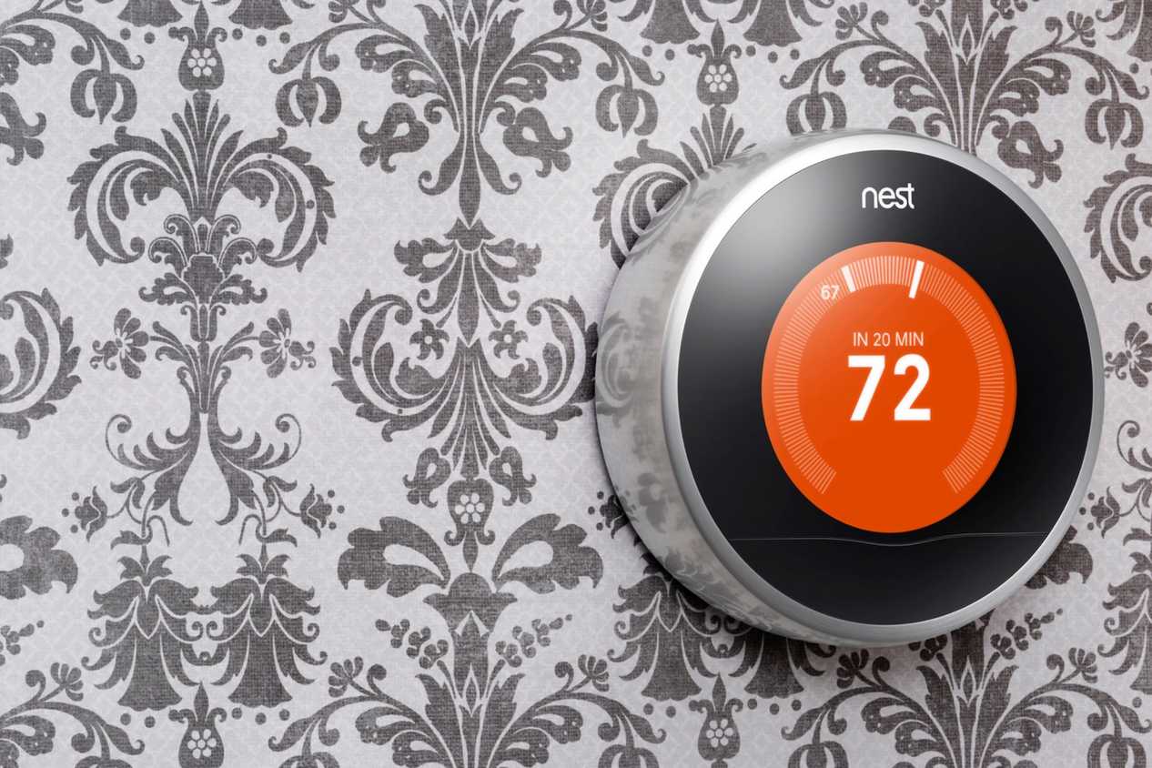 A first-generation Nest learning thermostat in a press image.