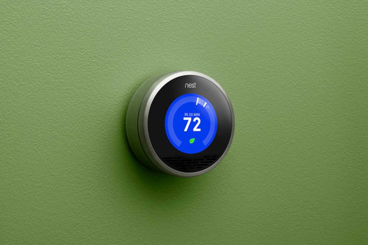 A first-generation Nest learning thermostat in a press image.