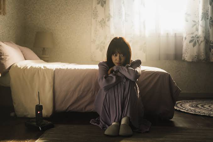 Character from The Call sitting by the bed