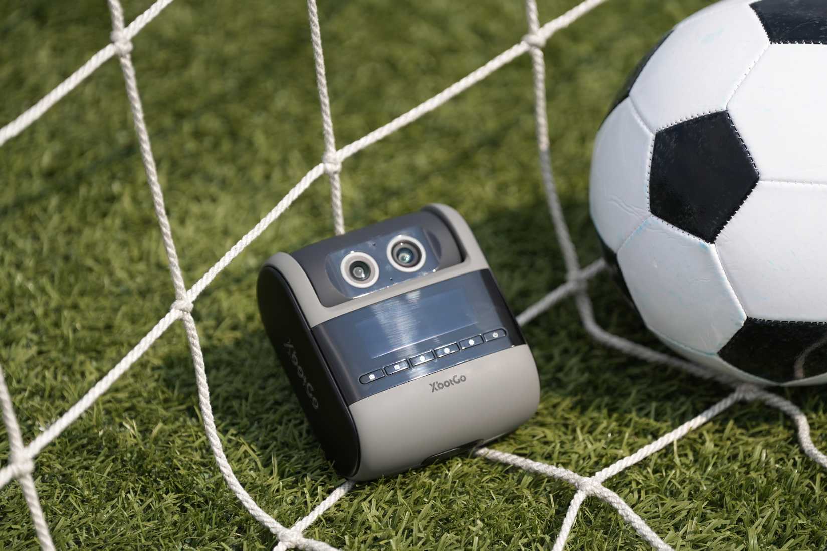 Closeup of the XbotGo Falcon camera resting in a net next to a soccer ball.