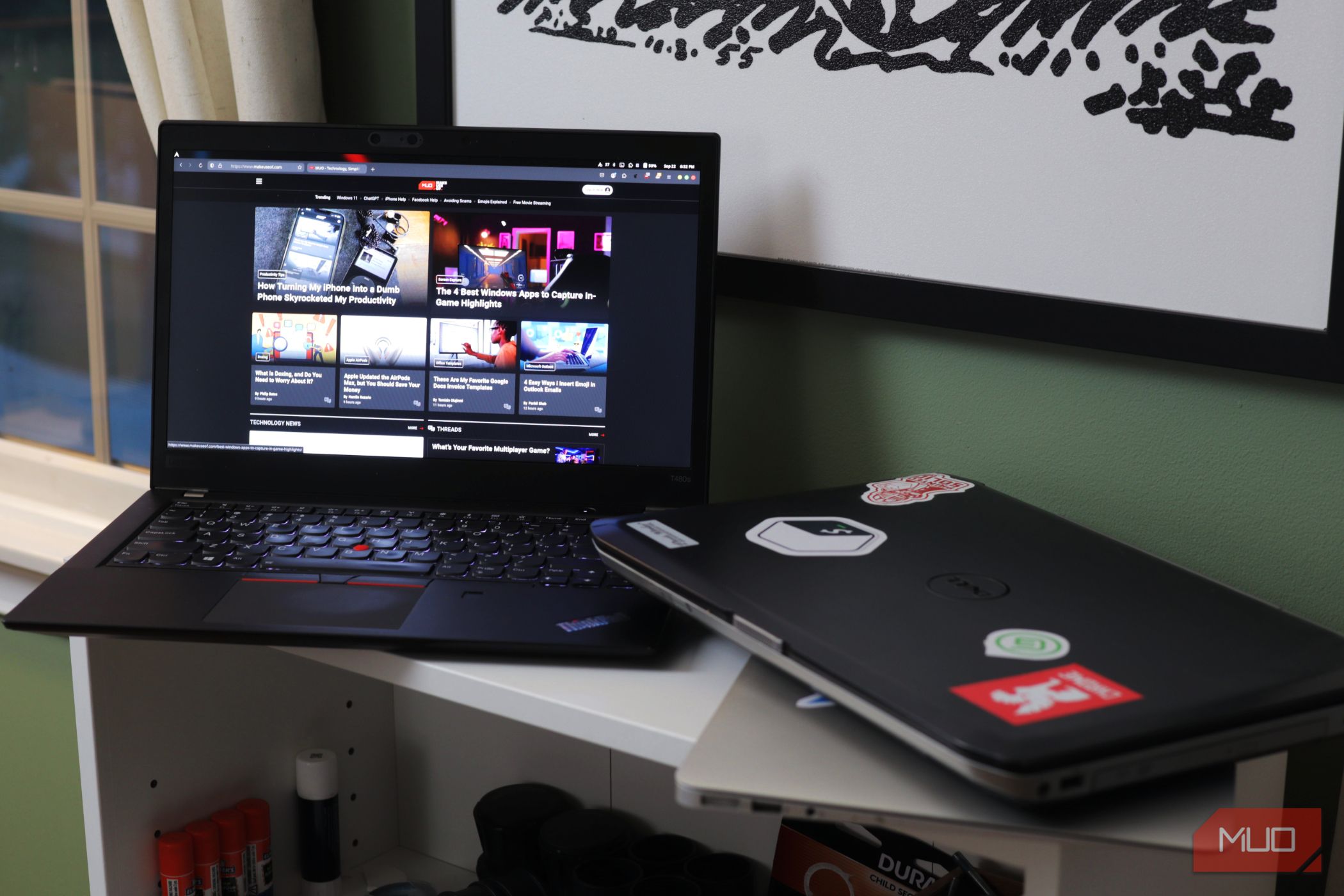 Two laptops on a white shelf with one opened to MakeUseOf