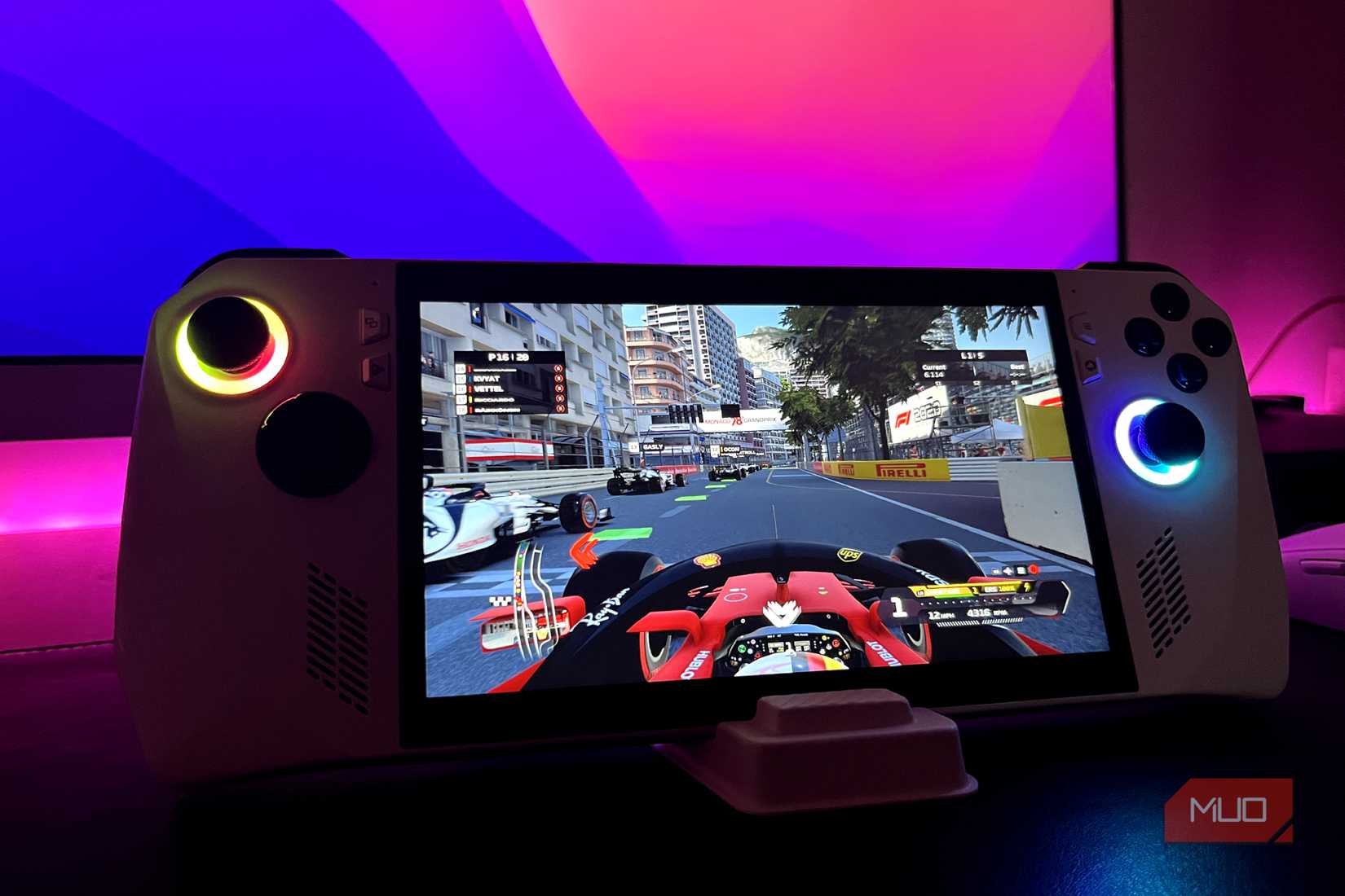ASUS ROG Ally on a stand with a monitor in the background