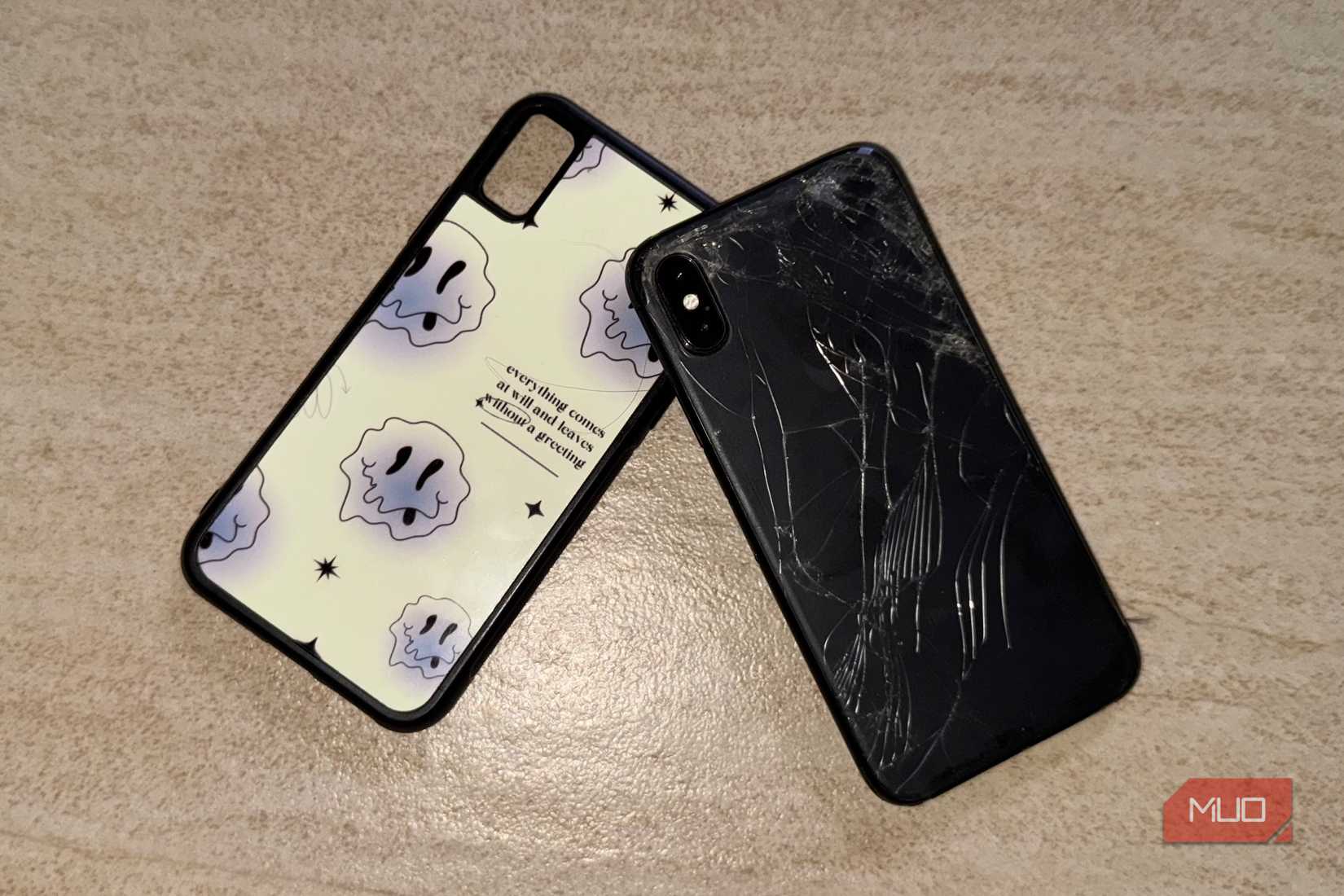 iPhone X with a cracked back glass lying on the floor with a case