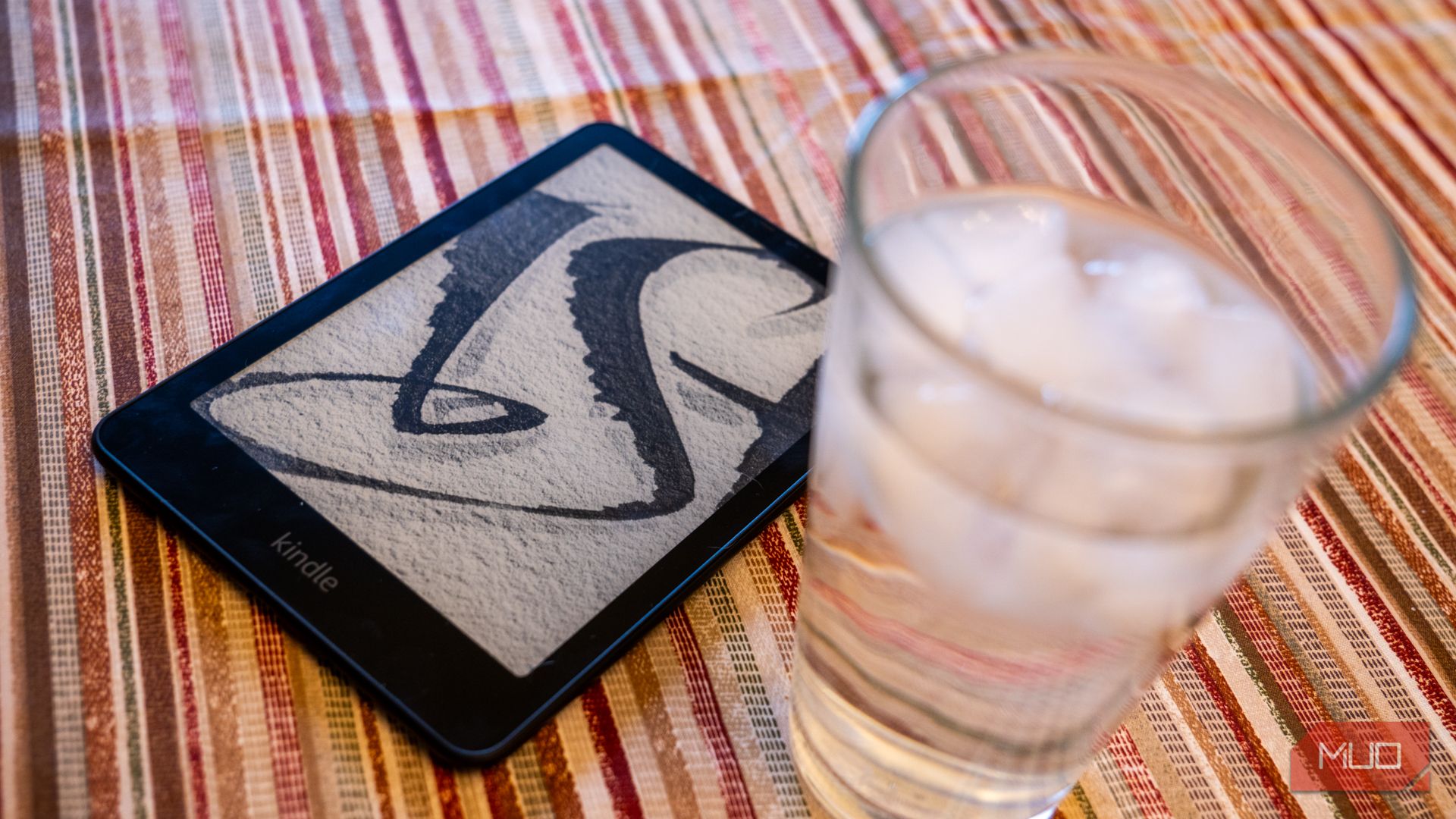 Amazon Kindle Paperwhite Signature Edition next to a glass of water.