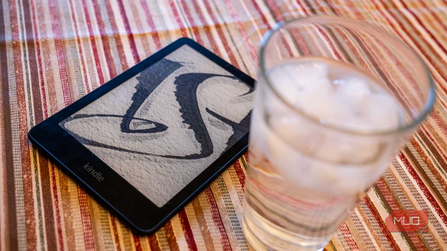 Amazon Kindle Paperwhite Signature Edition next to a glass of water.
