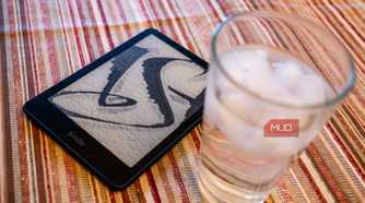 Amazon Kindle Paperwhite Signature Edition next to a glass of water.