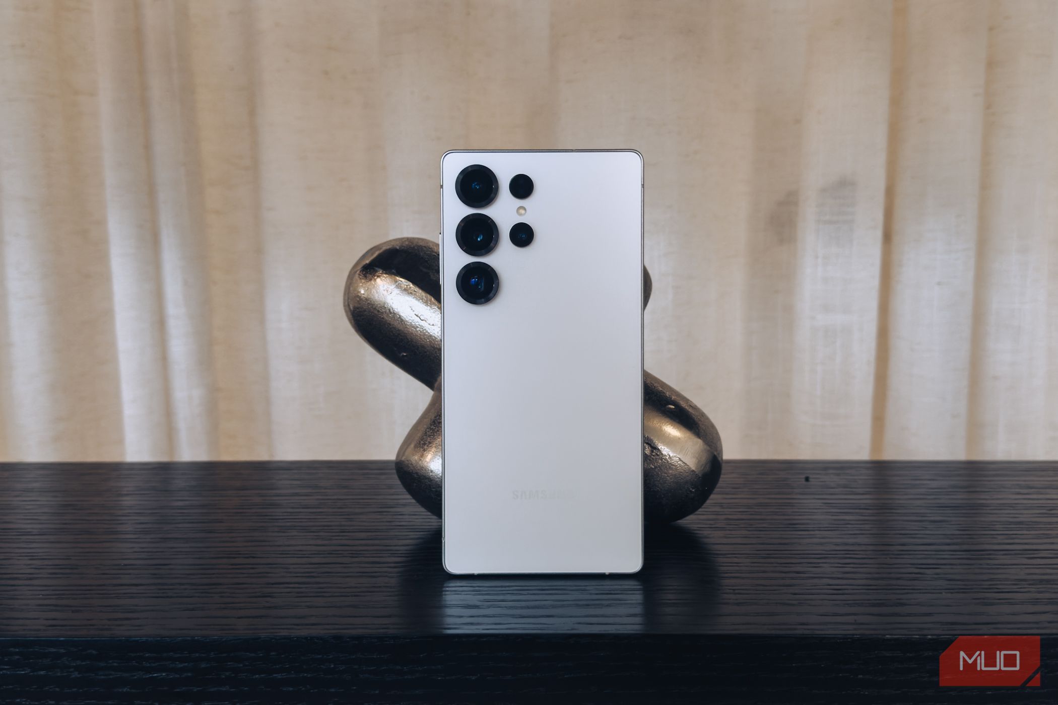 Samsung Galaxy S25 Ultra in White against a black bookshelf.