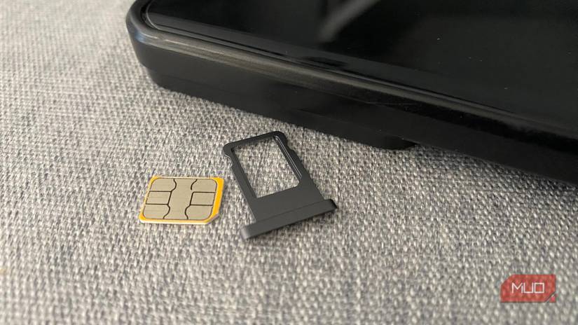 A SIM card and plastic holder laying next to a cell phone on a table