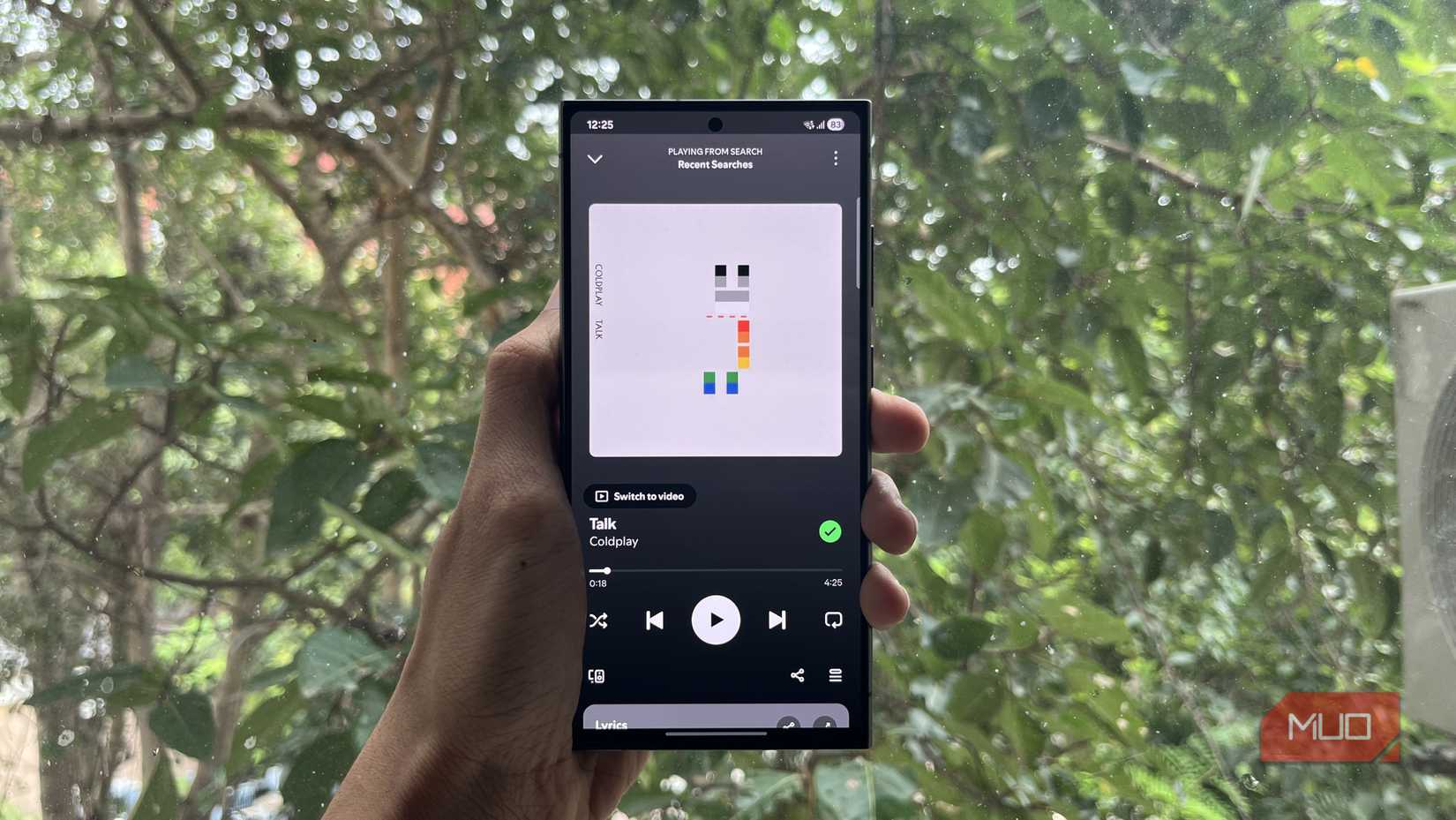 A person holding a Samsung phone with Spotify open.