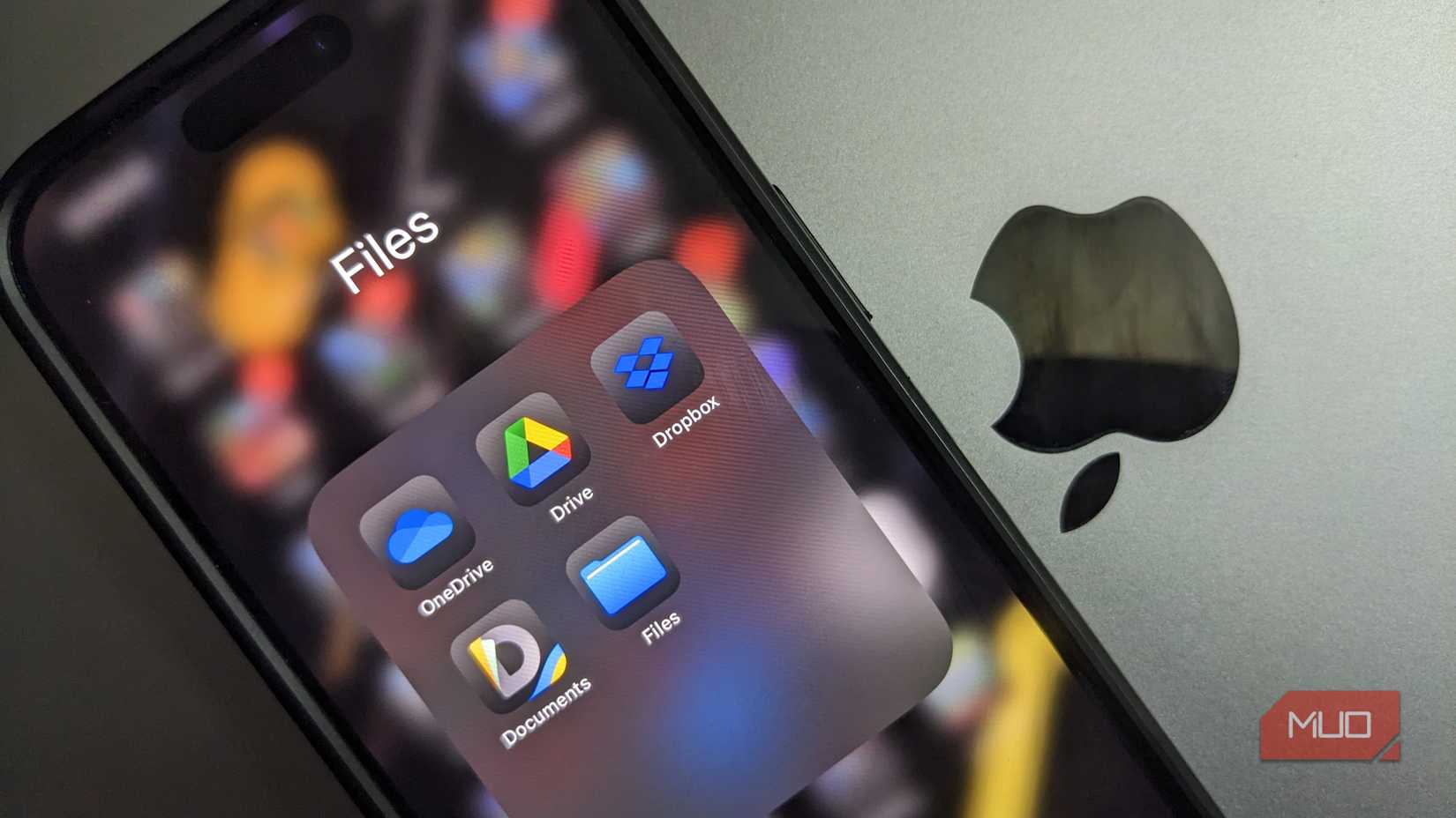 Cloud Storage Apps Folder on an iPhone on Top of a MacBook With the Apple Logo