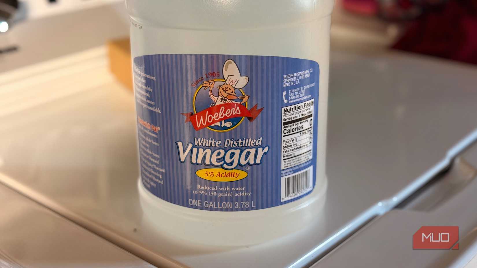 A bottle of vinegar sitting on the top of a washing machine.