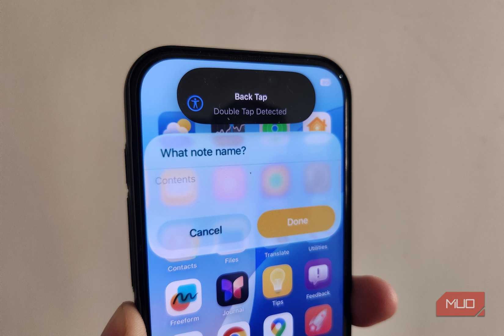 iPhone 16 Pro in hand showing Back Tap activated alert