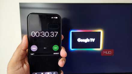 iPhone in hand running a stopwatch with Google TV booting in background