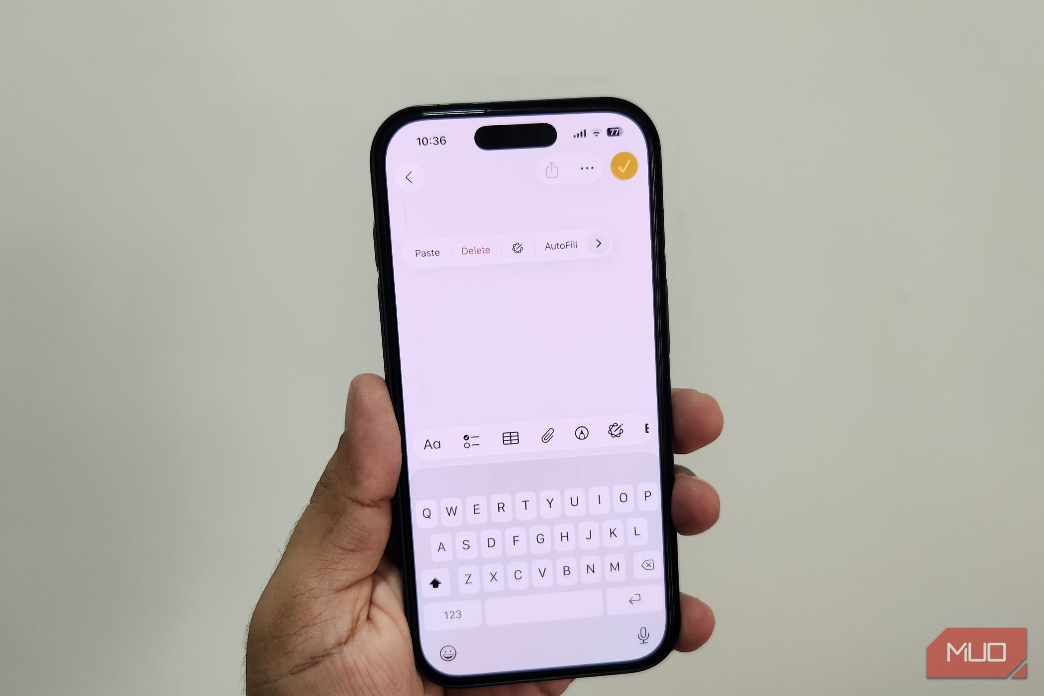 iPhone in hand showing keyboard and paste option in notes app