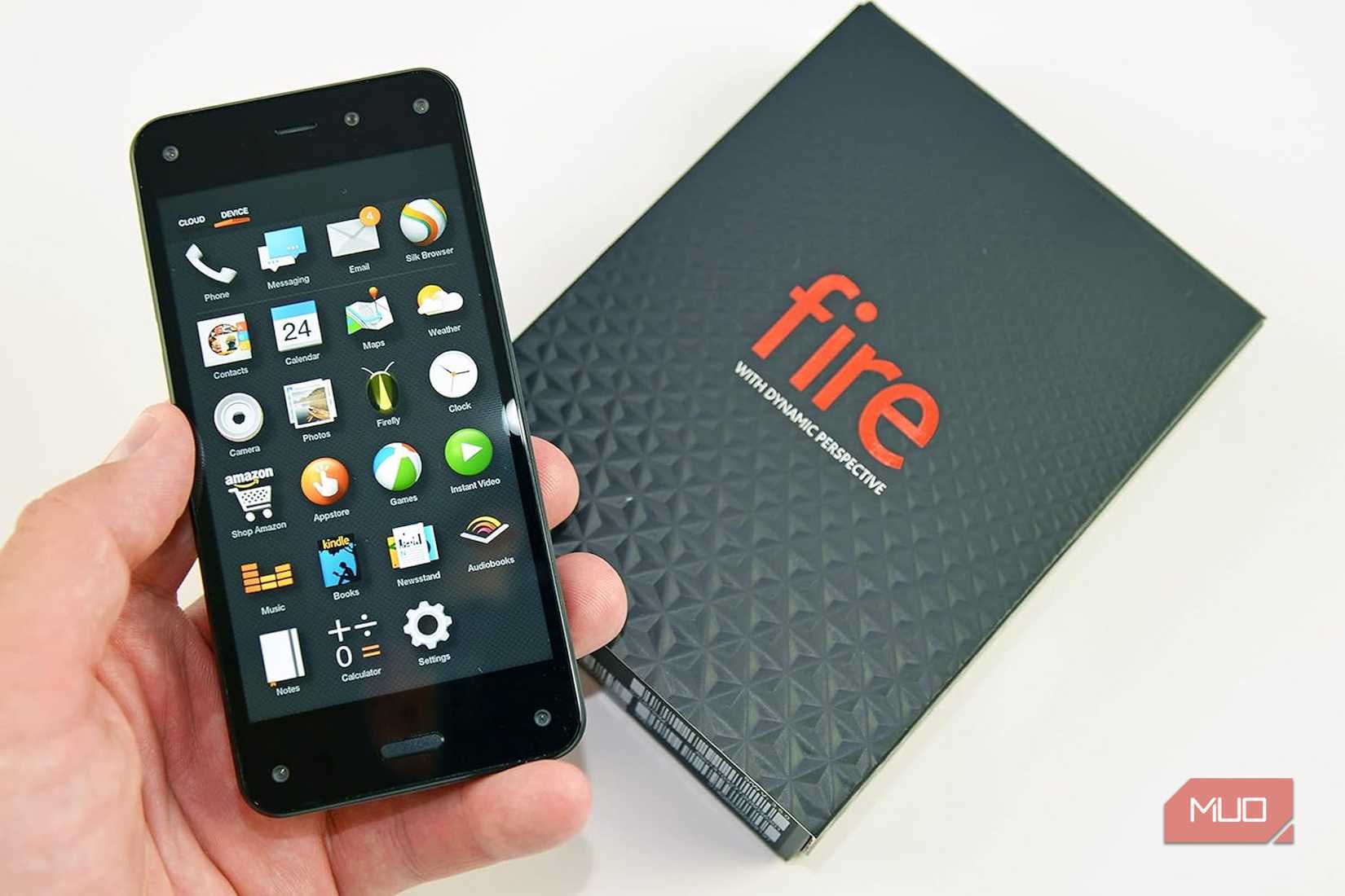 A hand holding a Fire phone next to its box.