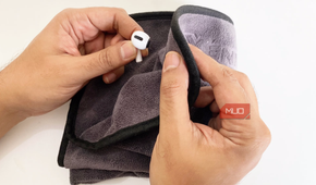 A person wipes down their earbuds with a microfiber cloth.