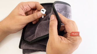 A person wipes down their earbuds with a microfiber cloth.