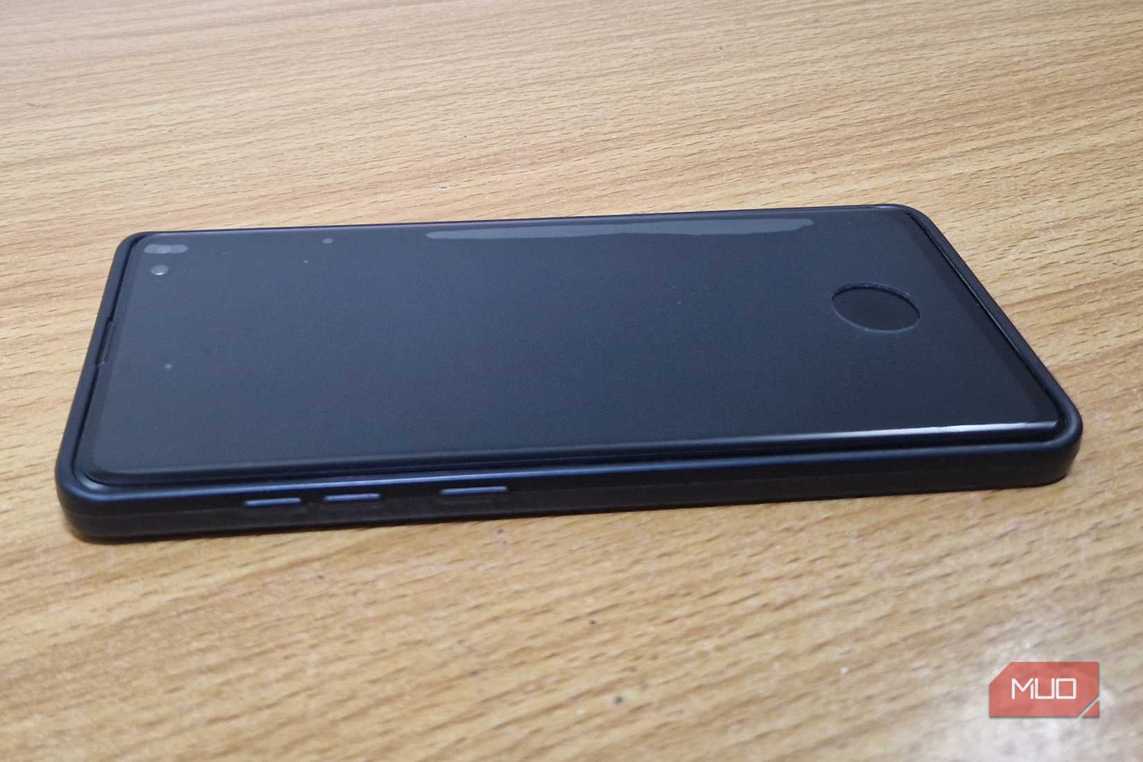 A screen protector with a fingerprint scanner cut out atop a Samsung phone on a table.