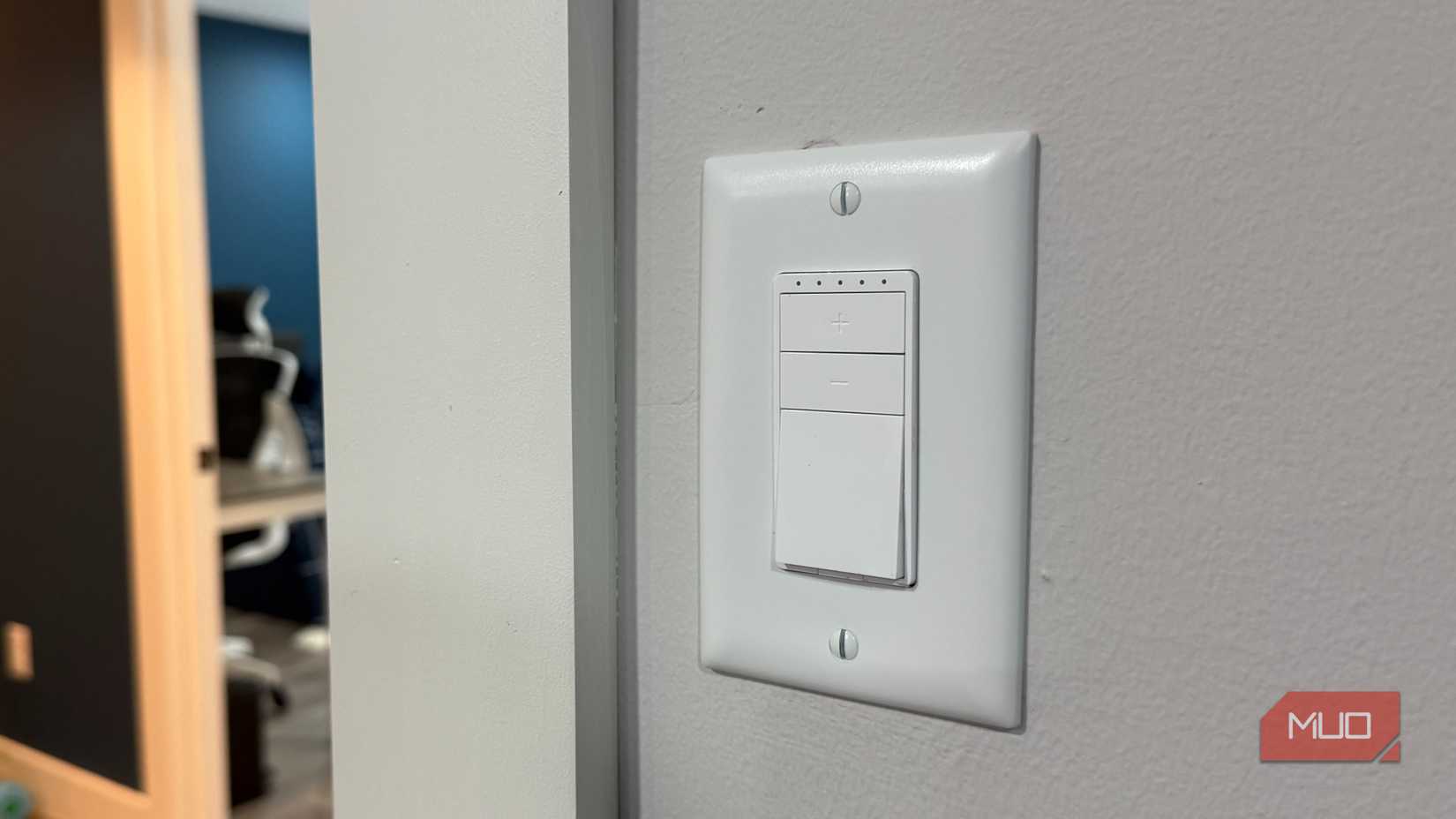 Interruptor de luz con botones más y menos junto a una puerta en una casa